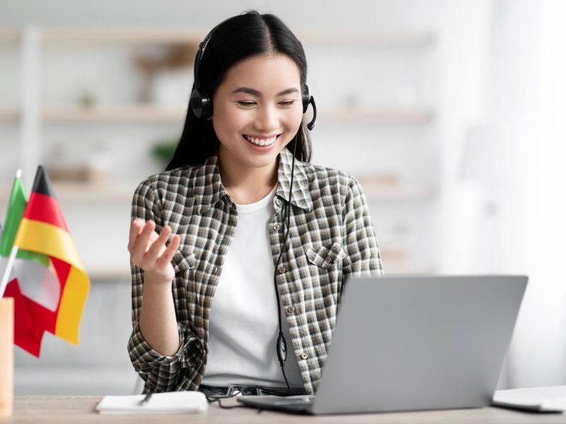 happy-asian-lady-using-laptop-and-headset-learning-foreign-language.jpg